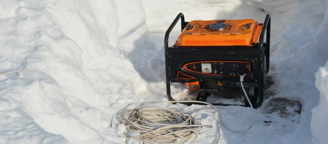 Portable generator outside in the snow with a coiled extension cord.